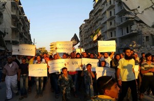 FILE - In this Tuesday, Sept. 13, 2016, file photo, activists in Syria's besieged Aleppo protest against the United Nations for what they say is its failure to lift the siege off their rebel-held area. A fragile cease-fire, brokered by the United States and Russia and now in its seventh day, has mostly held despite numerous violations. Banners read in Arabic: 'Hunger better than humiliation,' one banner read. 'X the UN'. (Modar Shekho via AP)