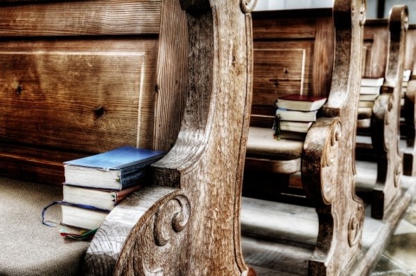 wooden seats in an antique church with books on it