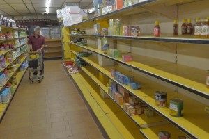 CARACAS, VENEZUELA - JANUARY 13: A shopper walks past nearly empty shelves at a supermarket due to a long term shortage in Caracas, Venezuela on January 13, 2015. Sliding oil prices have sent Venezuela on a downward spiral and sent President Nicolas Maduro on a trip to China to make an urgent appeal for cash. Country's economic woes have triggered severe shortages of some staple product, with government-controlled supermarkets now limiting the amount of certain products customers can purchase. (Photo by Carlos Becerra/Anadolu Agency/Getty Images)
