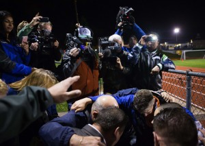 Coach Joe Kennedy, in blue, bottom, takes a knee with a few others to do a quick prayer in the stands after the Bremerton Knights beat the Sequim Wolves at Memorial Stadium in Bremerton on Thursday, Oct. 29, 2015. Bremerton assistant football coach Joe Kennedy was placed on administrative leave on Wednesday following his decision to pray on the field after he was told not to by the school district. The Satanic Temple of Seattle announced this week that they planned to be at the game on Thursday after a 12th-grader at Bremerton High School had requested the group perform a satanic invocation.  (Lindsey Wasson / The Seattle Times)