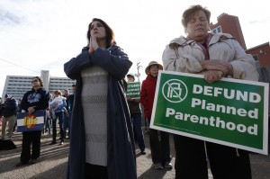 Participants in an anti-abortion rally hold signs and pray as they listen to a member of Christian clergy read from the Bible, in front of Planned Parenthood of the Rocky Mountains, in Denver, Saturday, Feb. 11, 2017. Anti-abortion activists emboldened by the new administration of President Donald Trump staged rallies around the country Saturday calling for the federal government to cut off payments to Planned Parenthood. (AP Photo/Brennan Linsley)