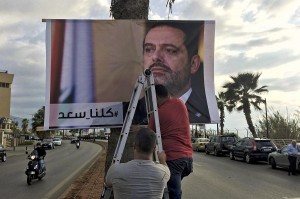 Workers hang a poster of outgoing Prime Minister Saad Hariri with Arabic words that read:"We are all Saad," at a seaside street in Beirut, Lebanon, Thursday, Nov. 9, 2017. Hezbollah has called on Saudi Arabia to stay out of Lebanese affairs, saying the resignation of Prime Minister Saad Hariri, announced from Riyadh over the weekend, "has raised many questions." (AP Photo/Hussein Malla)