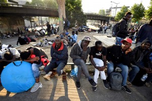 Migrants and refugees sit as they gather in the streets during the evacuation of a makeshift camp at Porte de la Chapelle, northern Paris, on July 7, 2017, one of several camps sprouting up around the French capital. French authorities proceeded to the evacuation of more than 2,000 migrants settled in a makeshift camp in the north of Paris, a few days before the presentation of a "migrant plan"  by the government. / AFP PHOTO / Eric FEFERBERG        (Photo credit should read ERIC FEFERBERG/AFP/Getty Images)