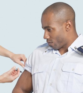 Young military man getting an injection from nurse over light blue background
